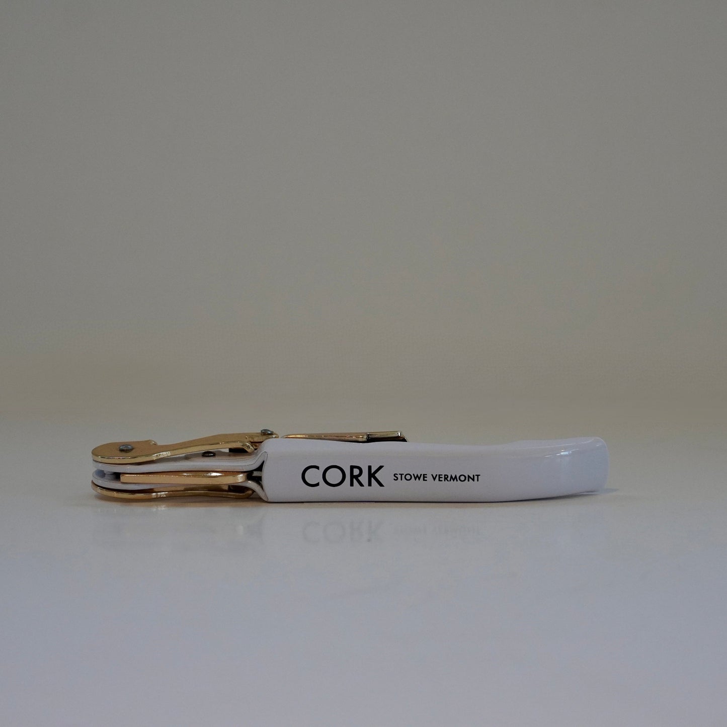 White keychain with gold clip and 'CORK' branding on a light gray background