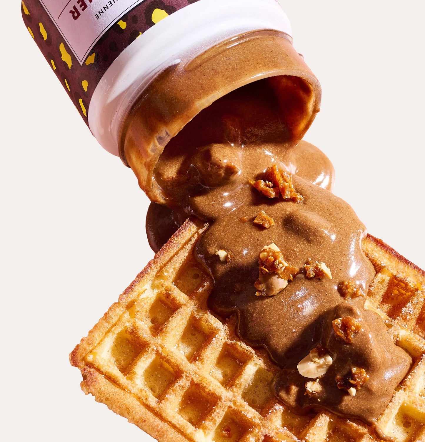 Jar of Nutella being poured onto a waffle