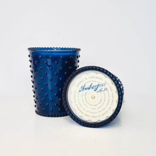 Blue textured candle with a white label on a light gray background