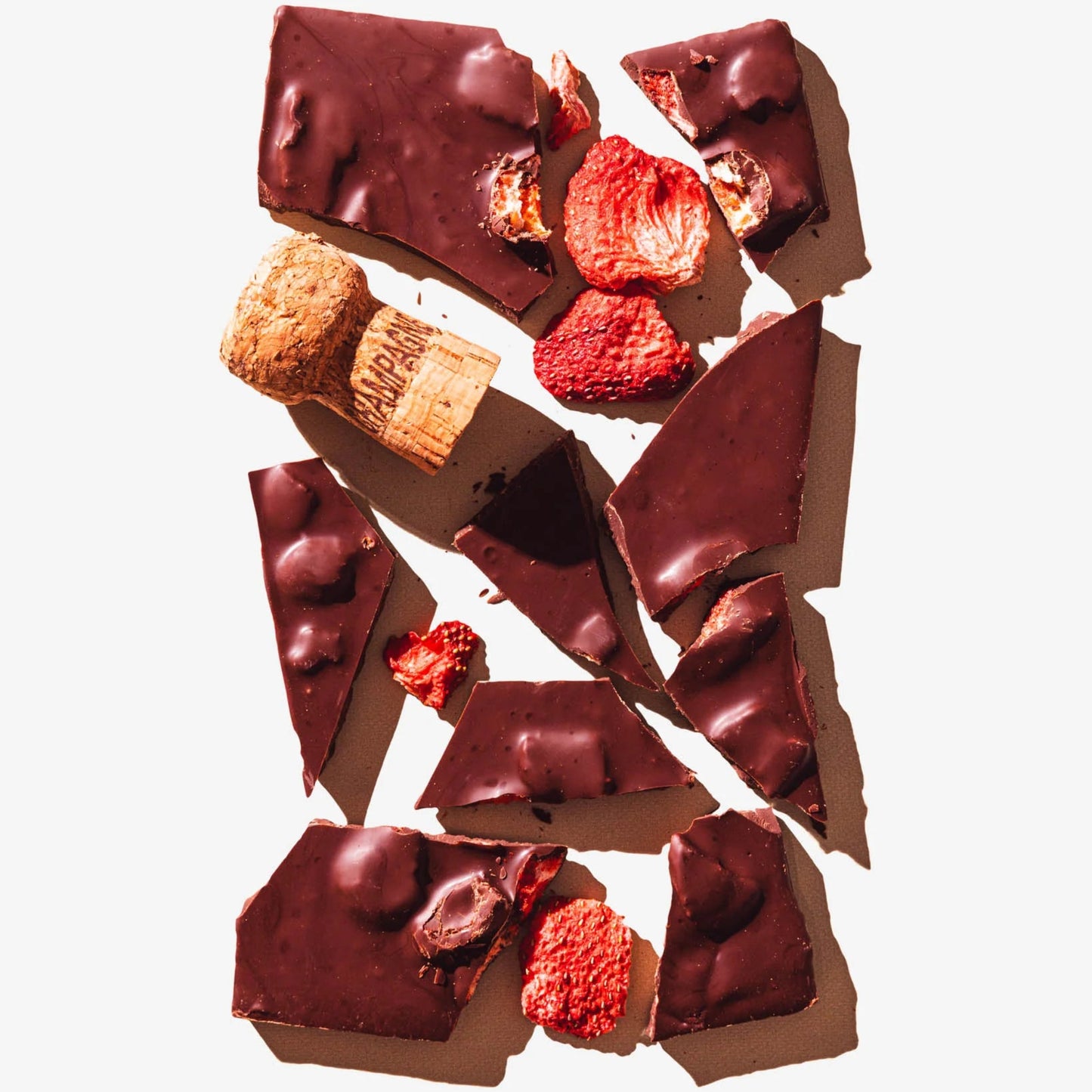 Chocolate pieces with nuts and berries on a white background