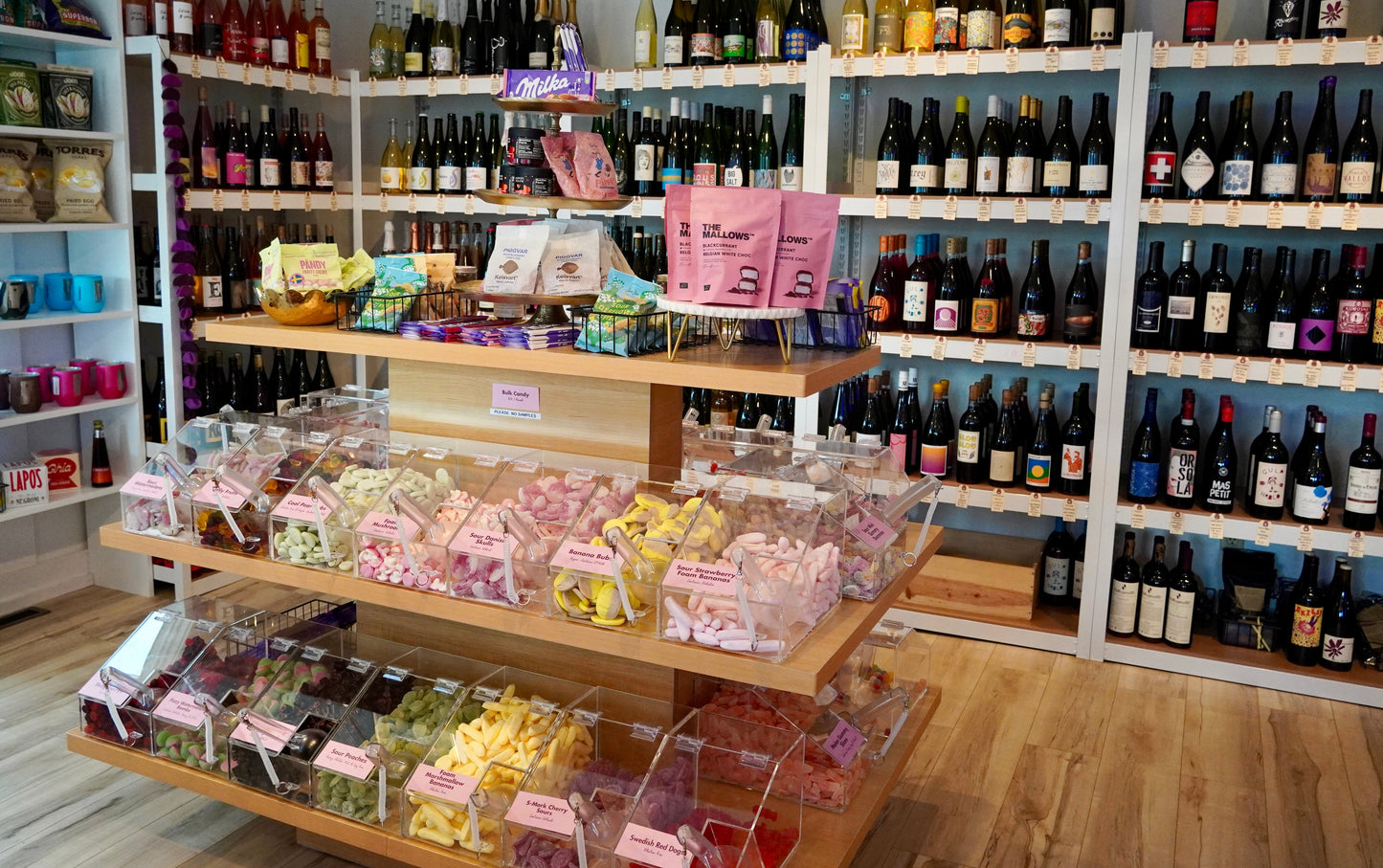Wine store interior with shelves stocked with bottles and a display of snacks.