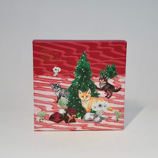 Decorative box with Christmas design featuring trees, animals, and snowflakes on a red background.