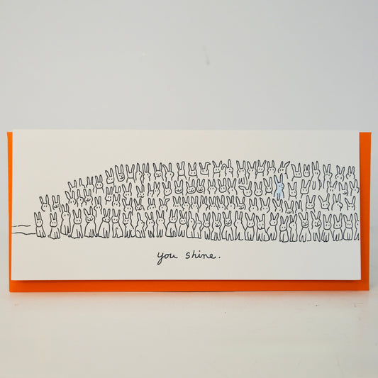 Framed artwork with a minimalist design of cats and the text 'you shine' on a white background.