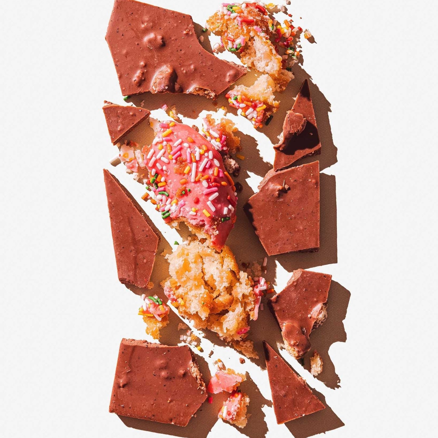Broken chocolate pieces with colorful toppings on a white background