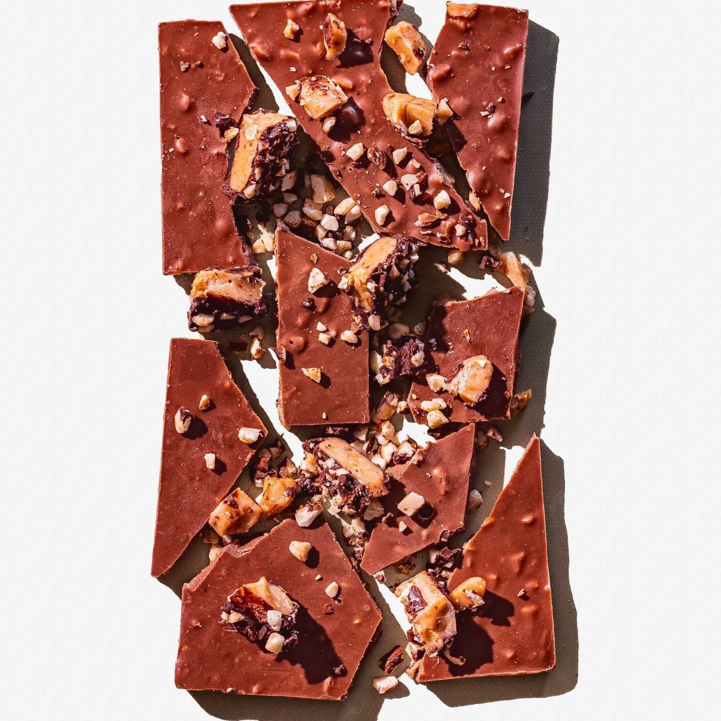 Broken pieces of chocolate with nuts on a light gray background