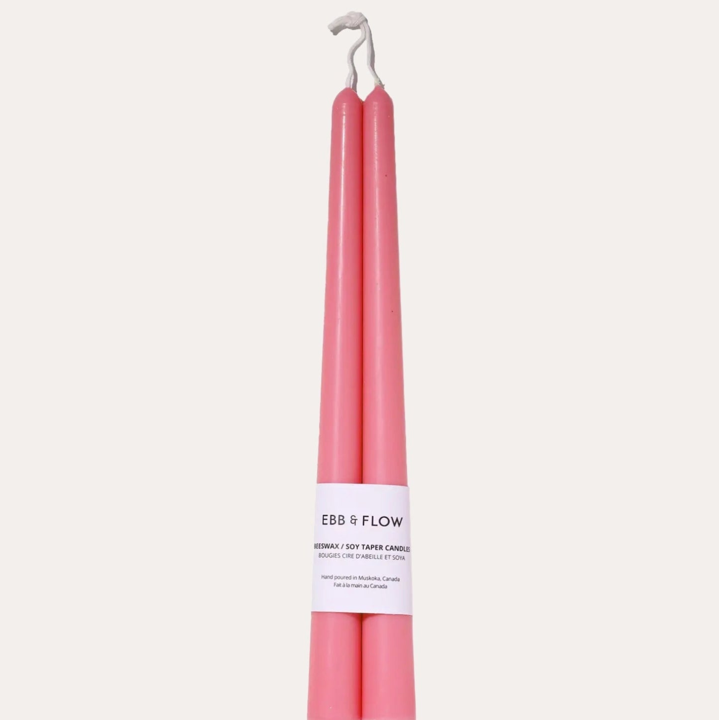 Two pink candles with a white label on a light gray background