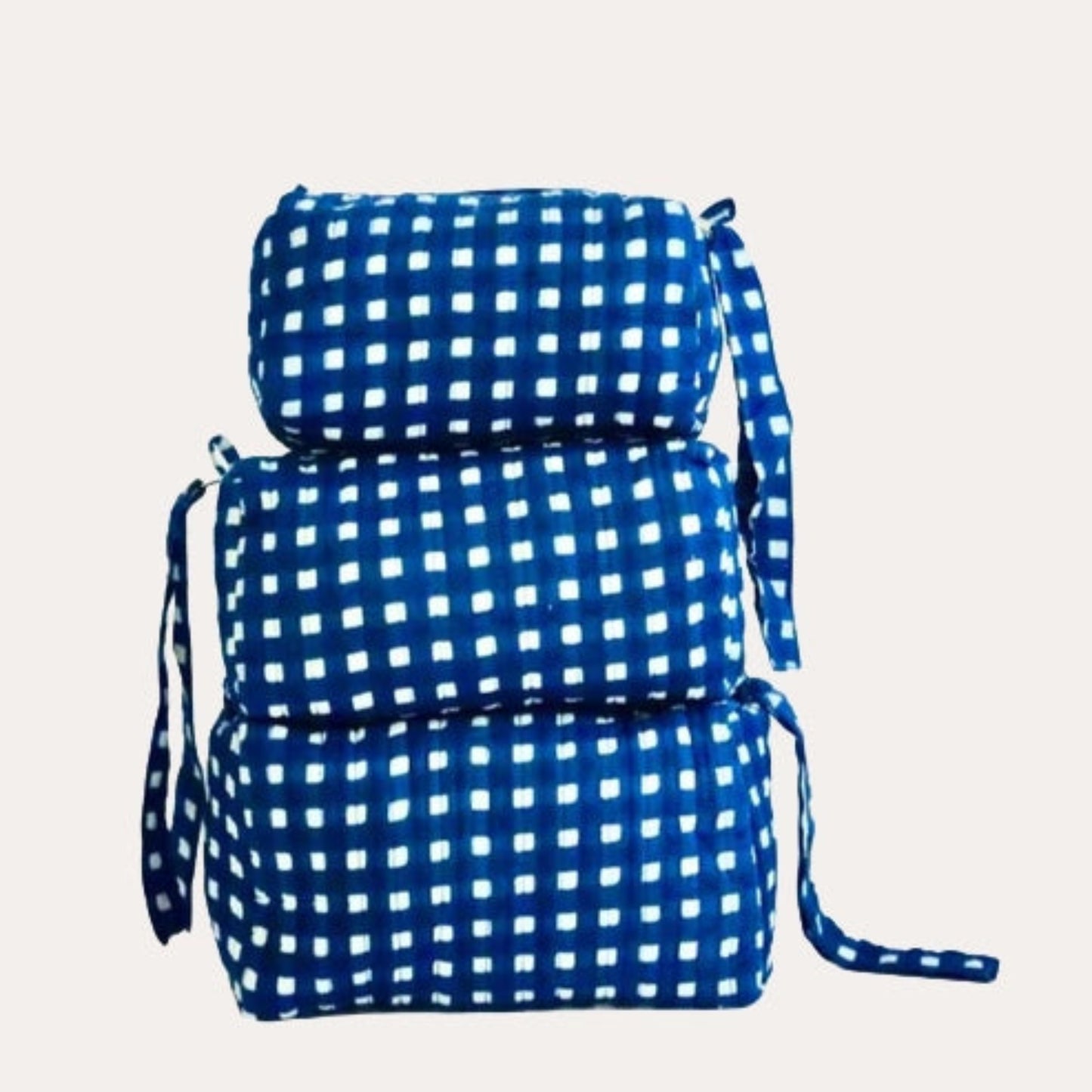 Set of three blue checkered cosmetic bags on a light gray background