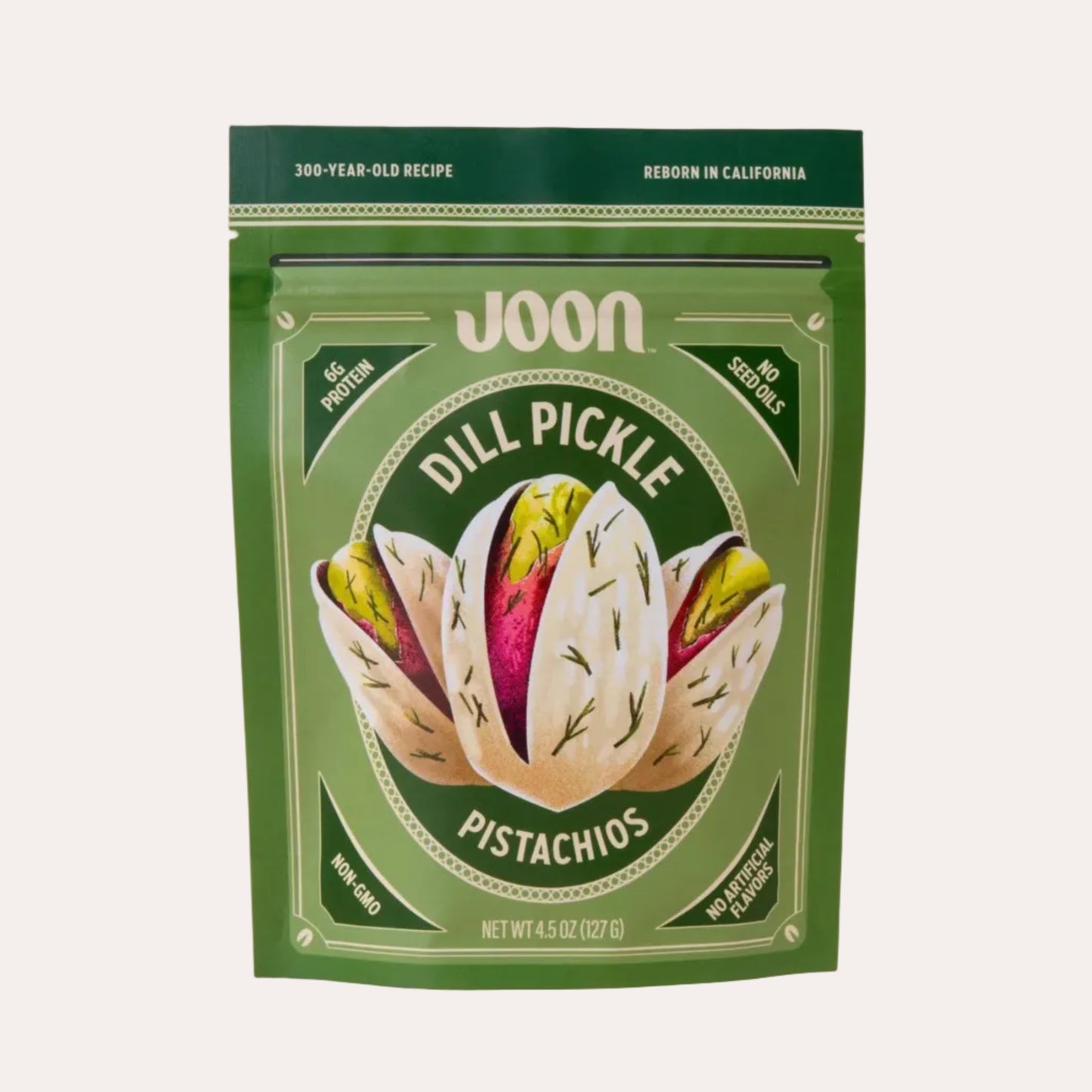Green package of JOON Dill Pickle Pistachios on a beige background