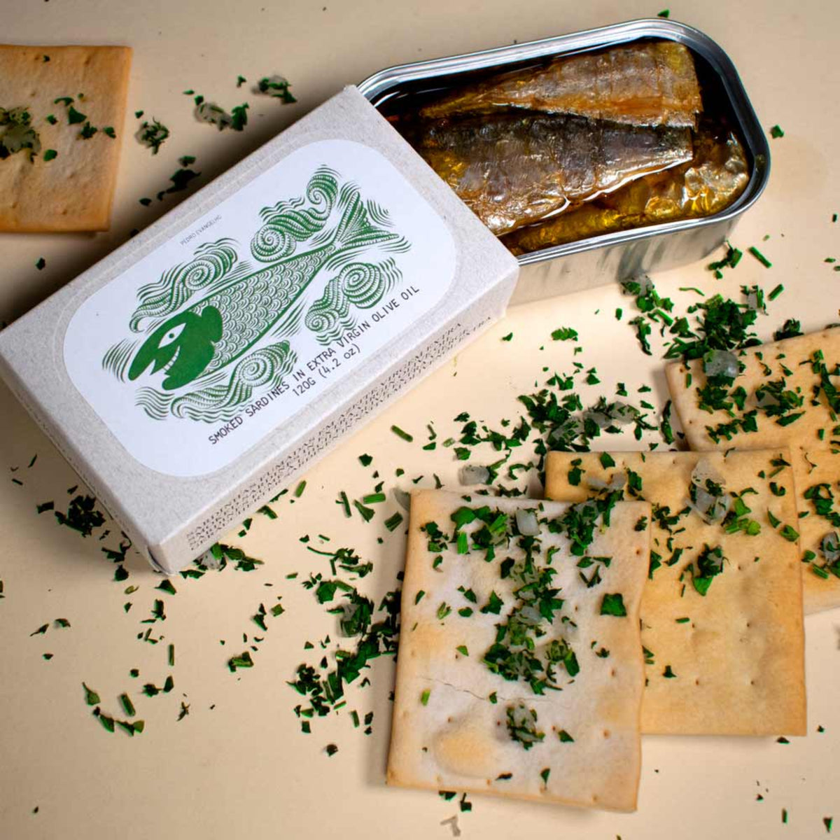 Tin of smoked sardines with crackers and herbs on a beige surface