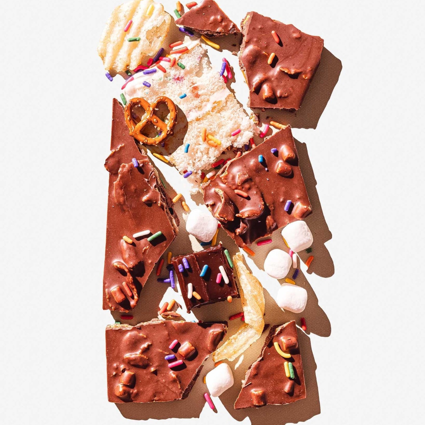 Assorted chocolate treats with sprinkles and marshmallows on a white background
