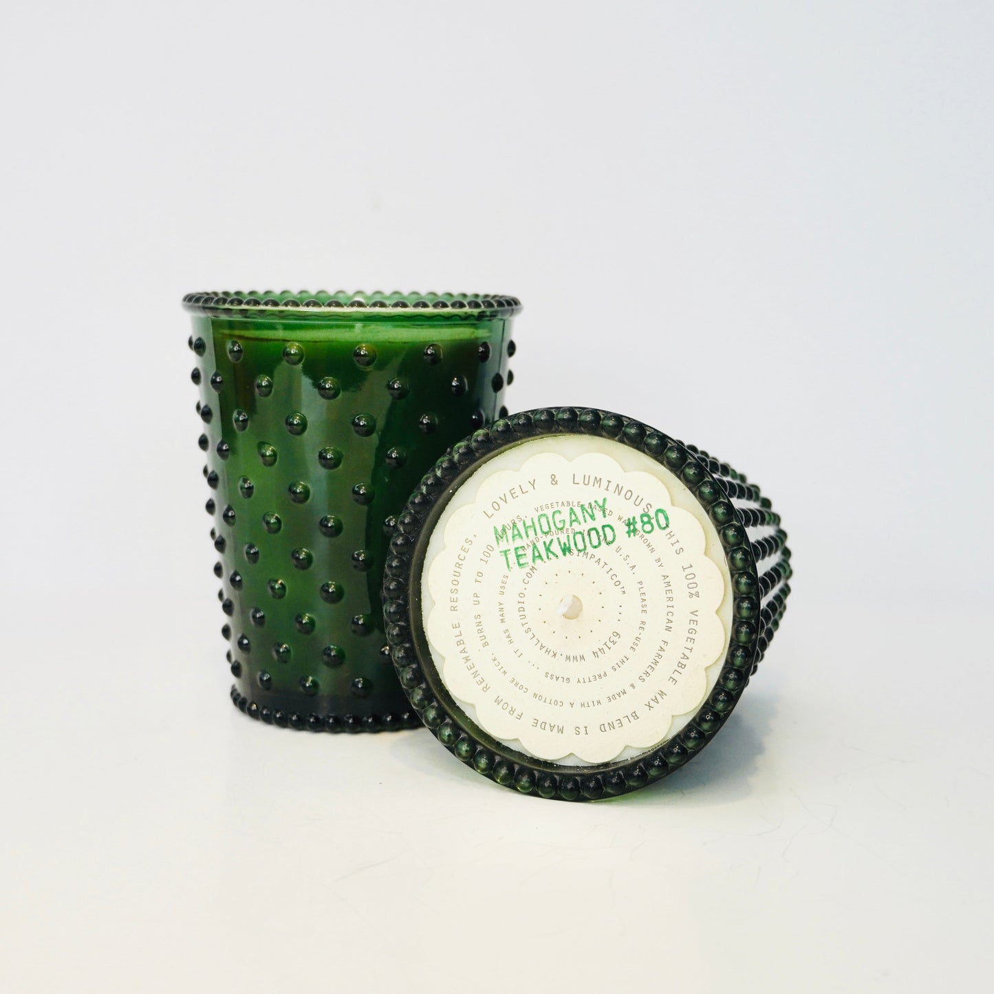 Green textured candle with a white label on a light gray background