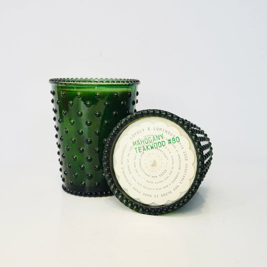 Green textured candle with a white label on a light gray background