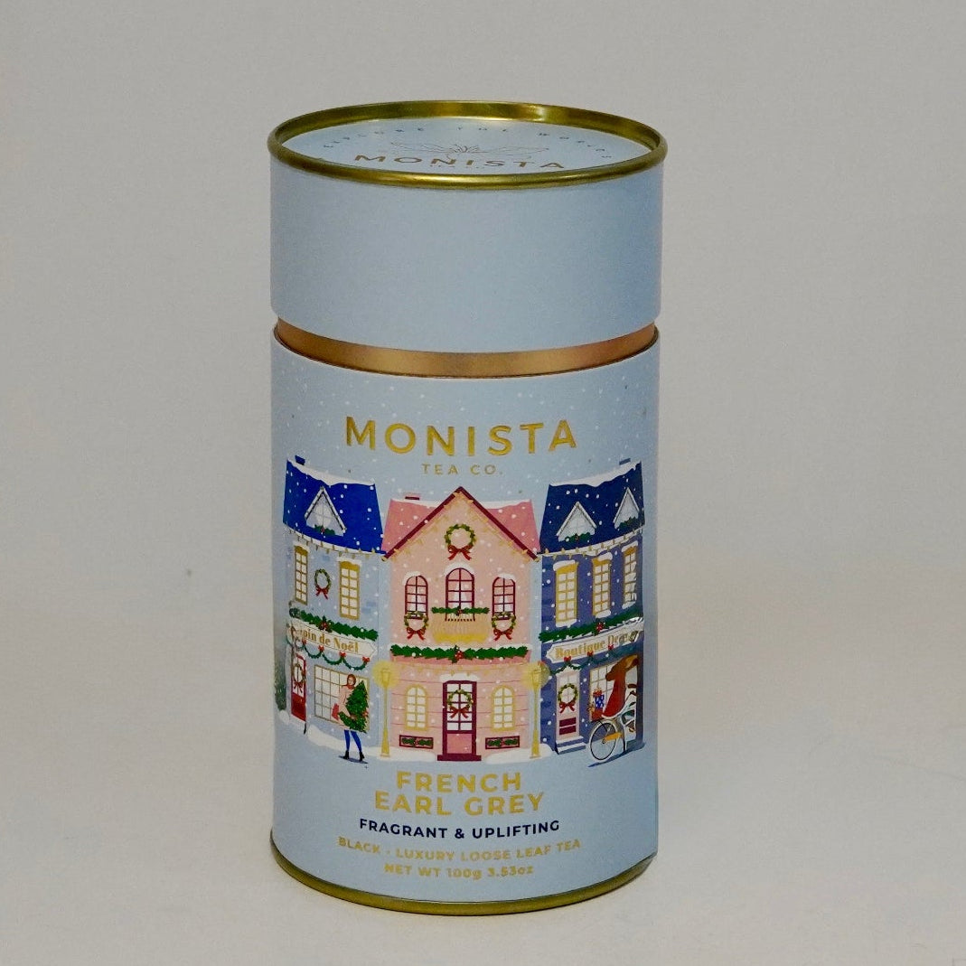 Small cylindrical tin with decorative design on a plain background