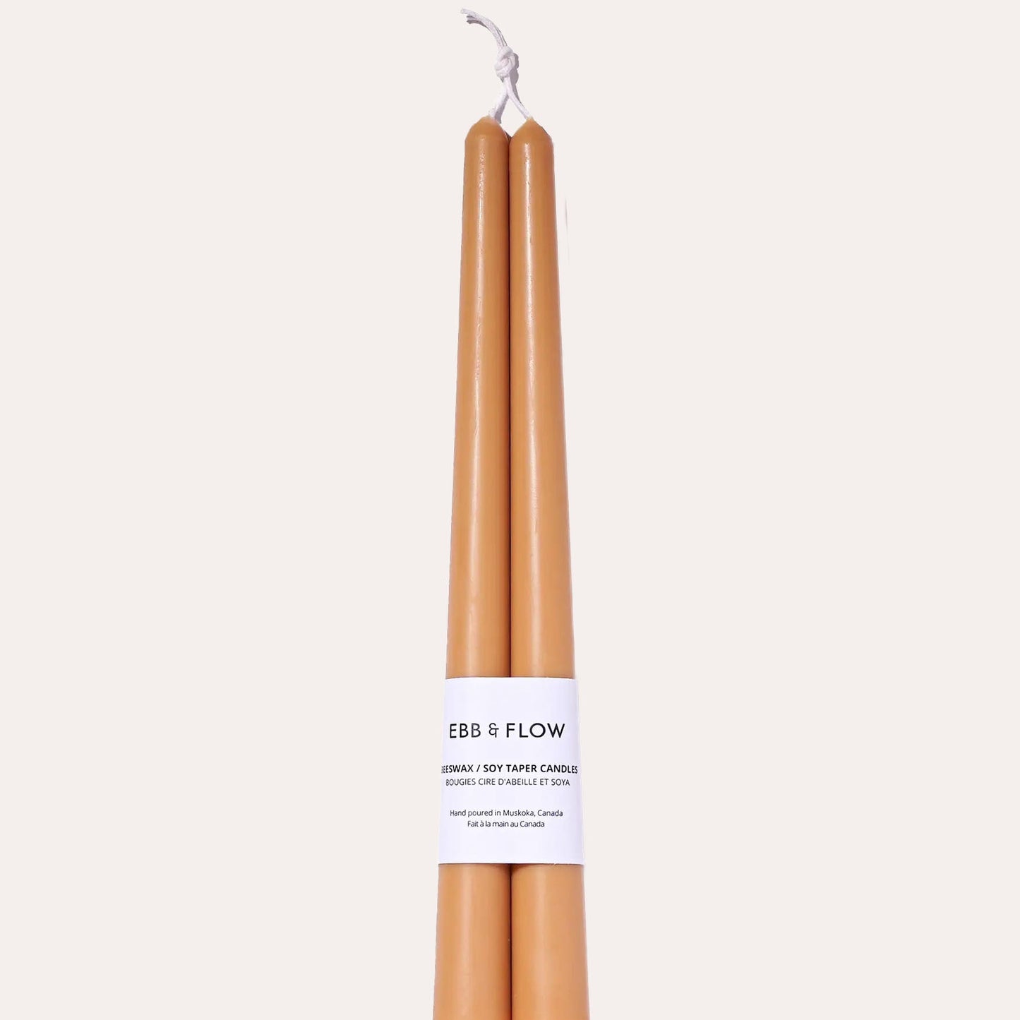 Two brown candles with a white label on a beige background
