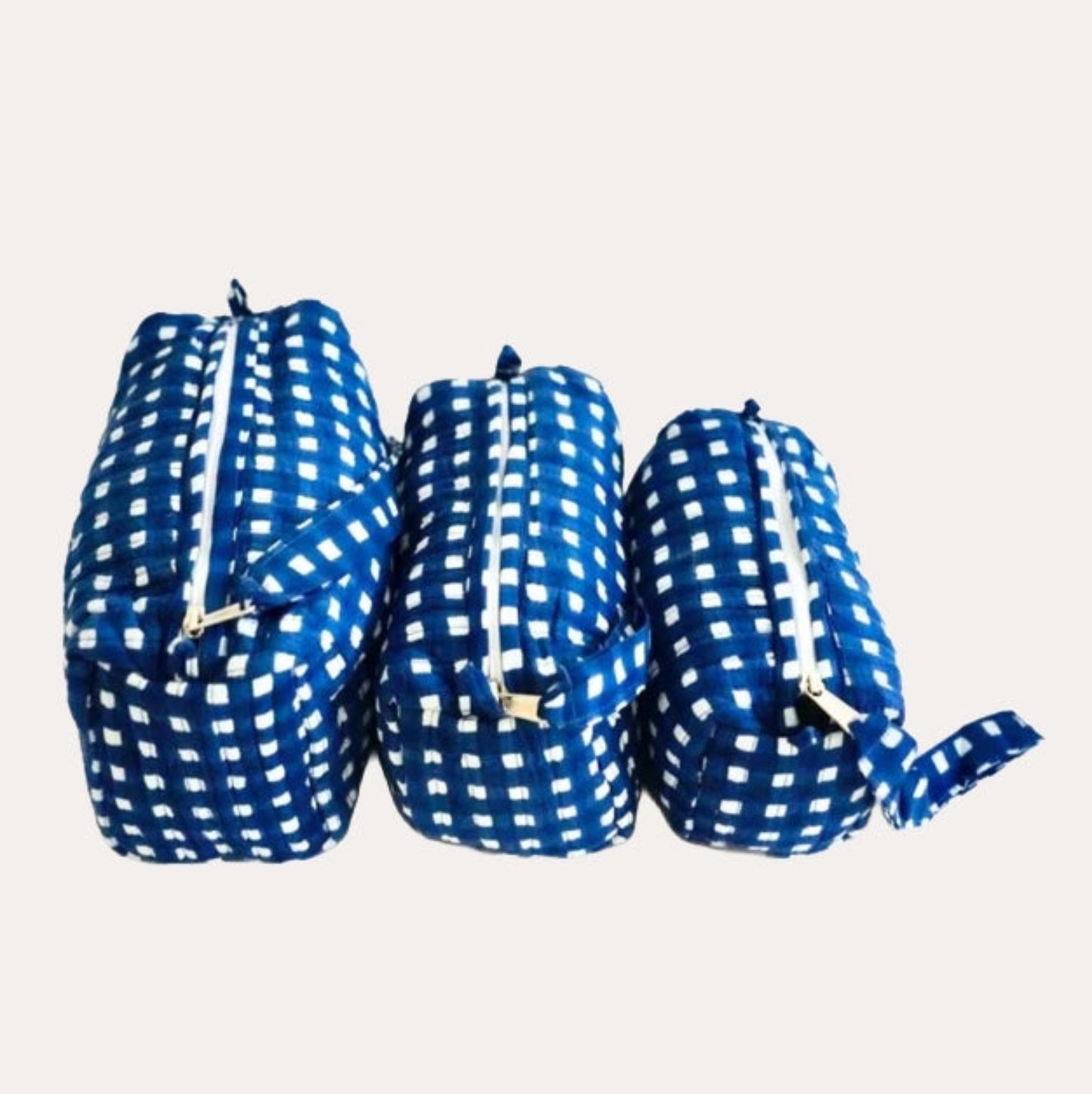 Three blue and white checkered cosmetic bags on a light gray background
