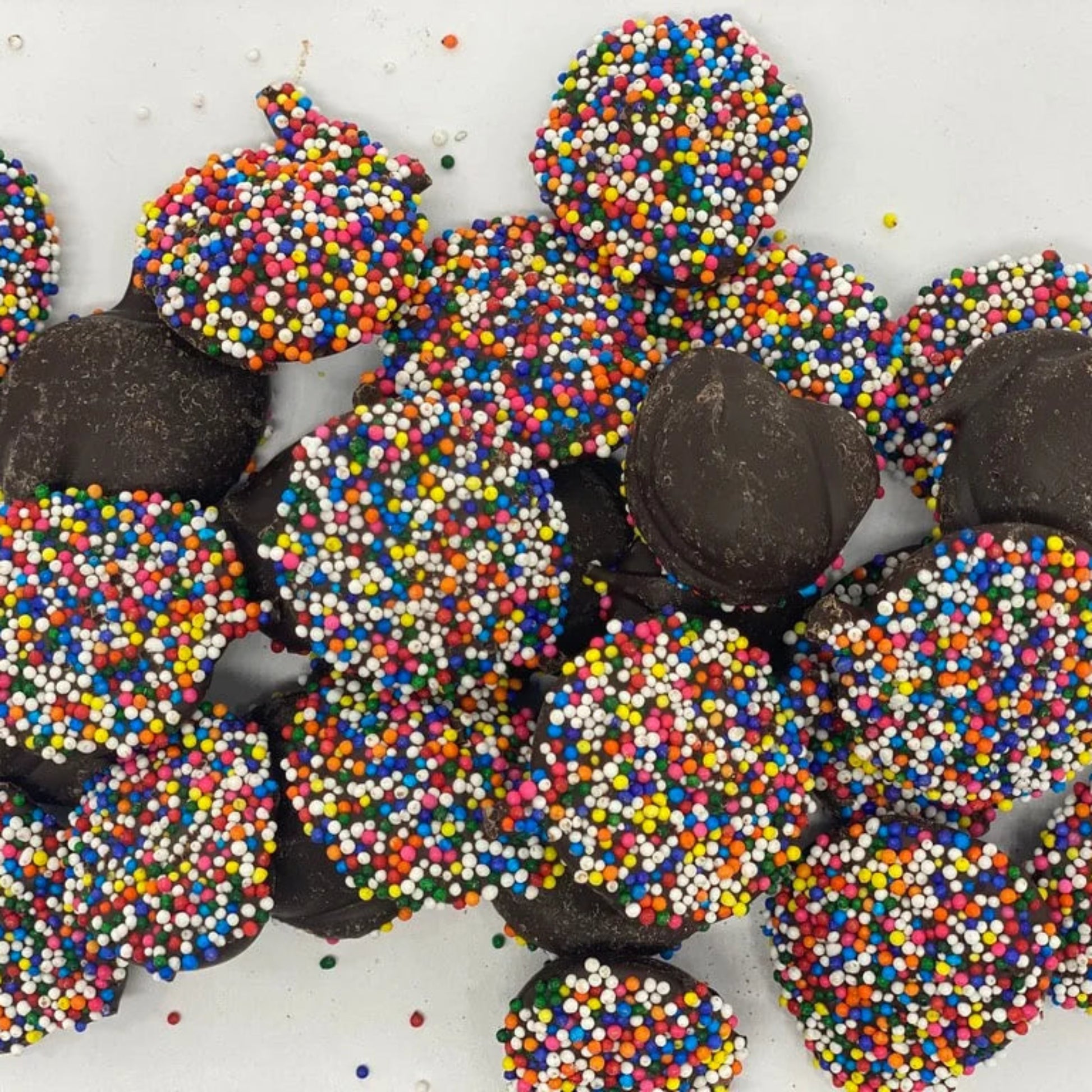 Chocolate truffles with colorful sprinkles on a white background