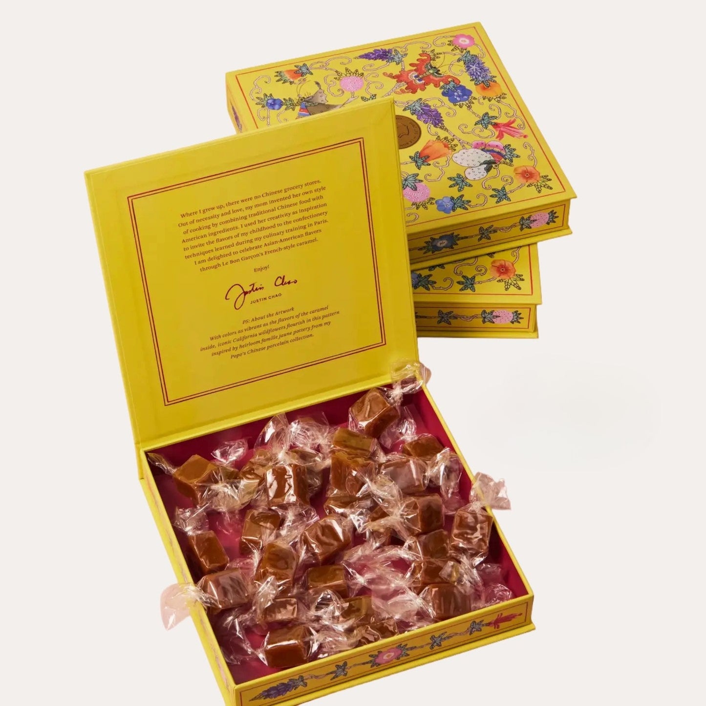 Open yellow box filled with caramels and a decorative lid on a white background