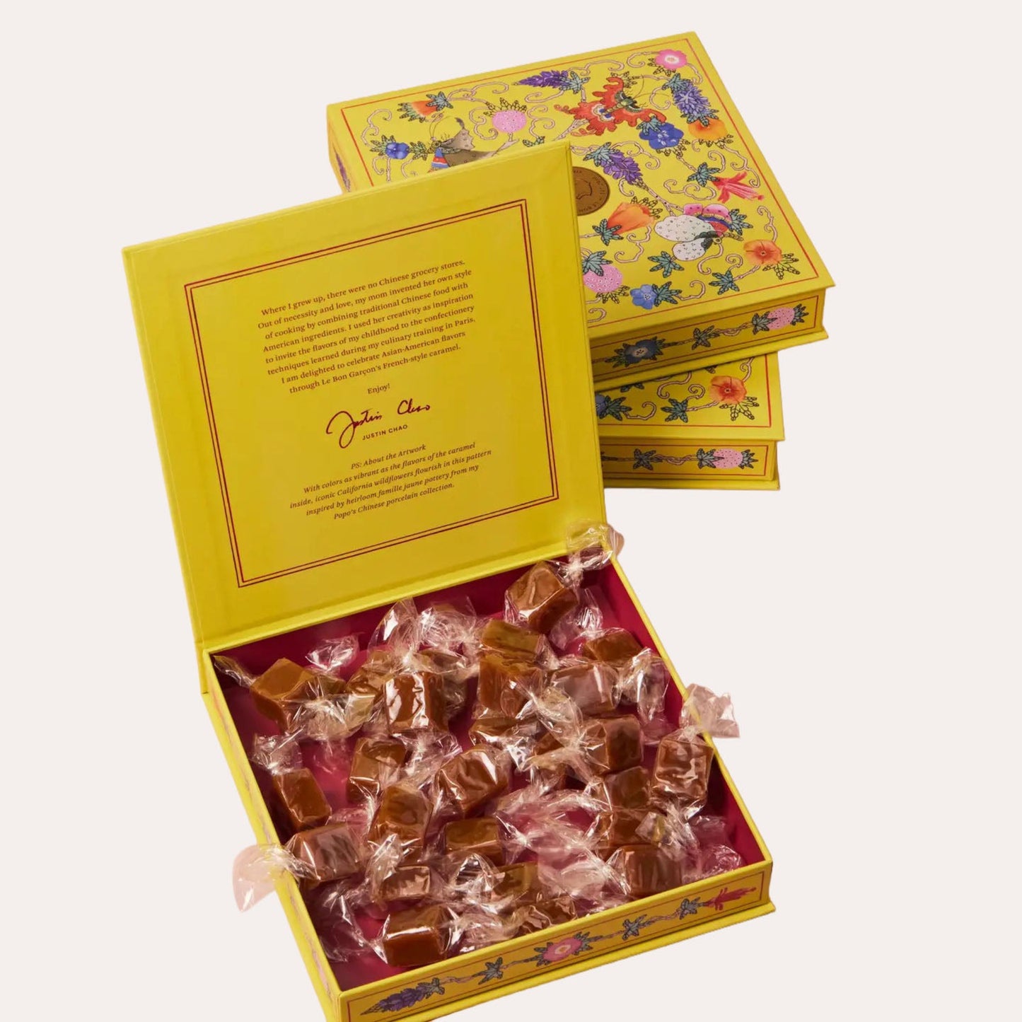 Open yellow box filled with caramels and a floral-patterned lid on a white background
