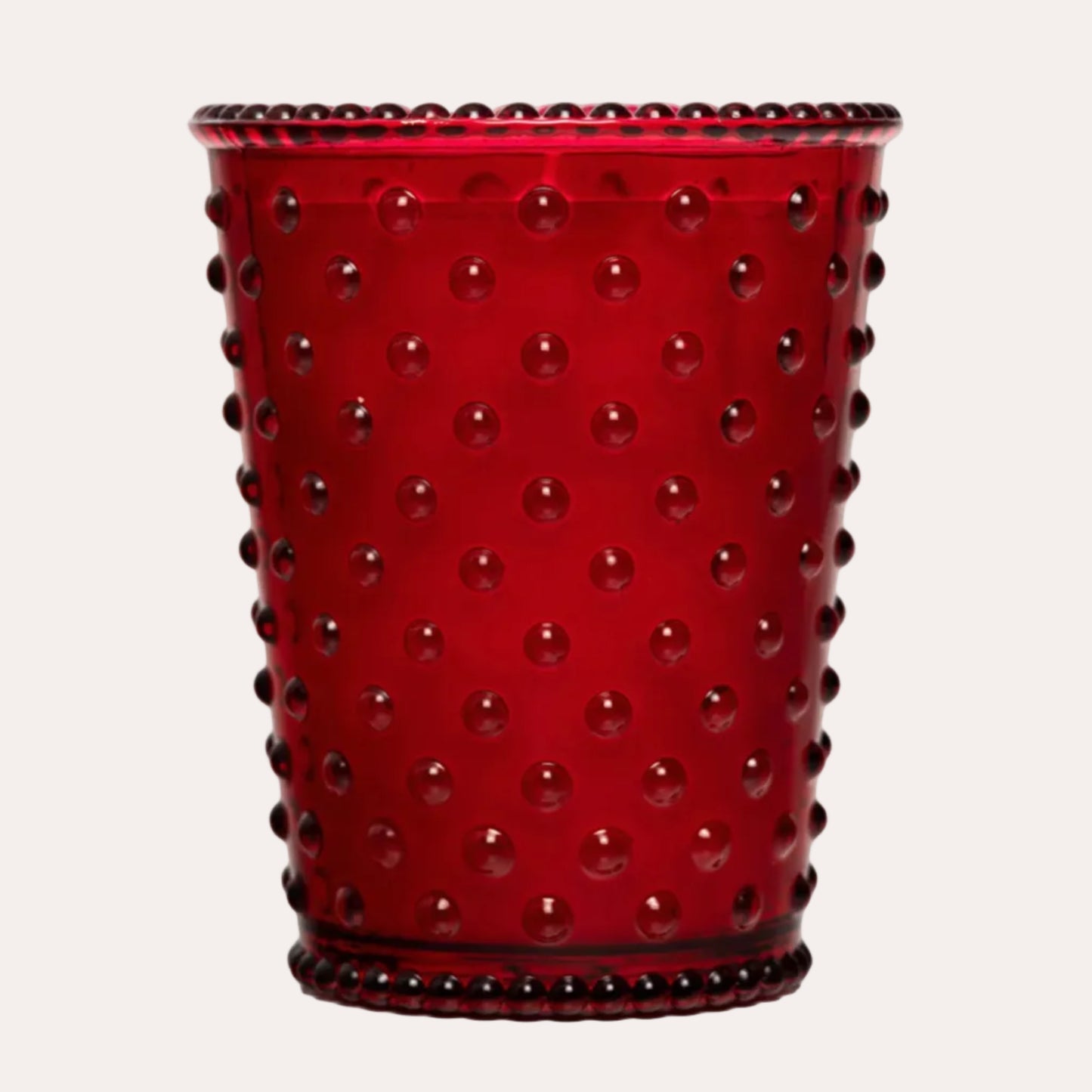 A red glass cup with a textured hobnail pattern of raised circular dots and a beaded rim, shown on a plain white background.