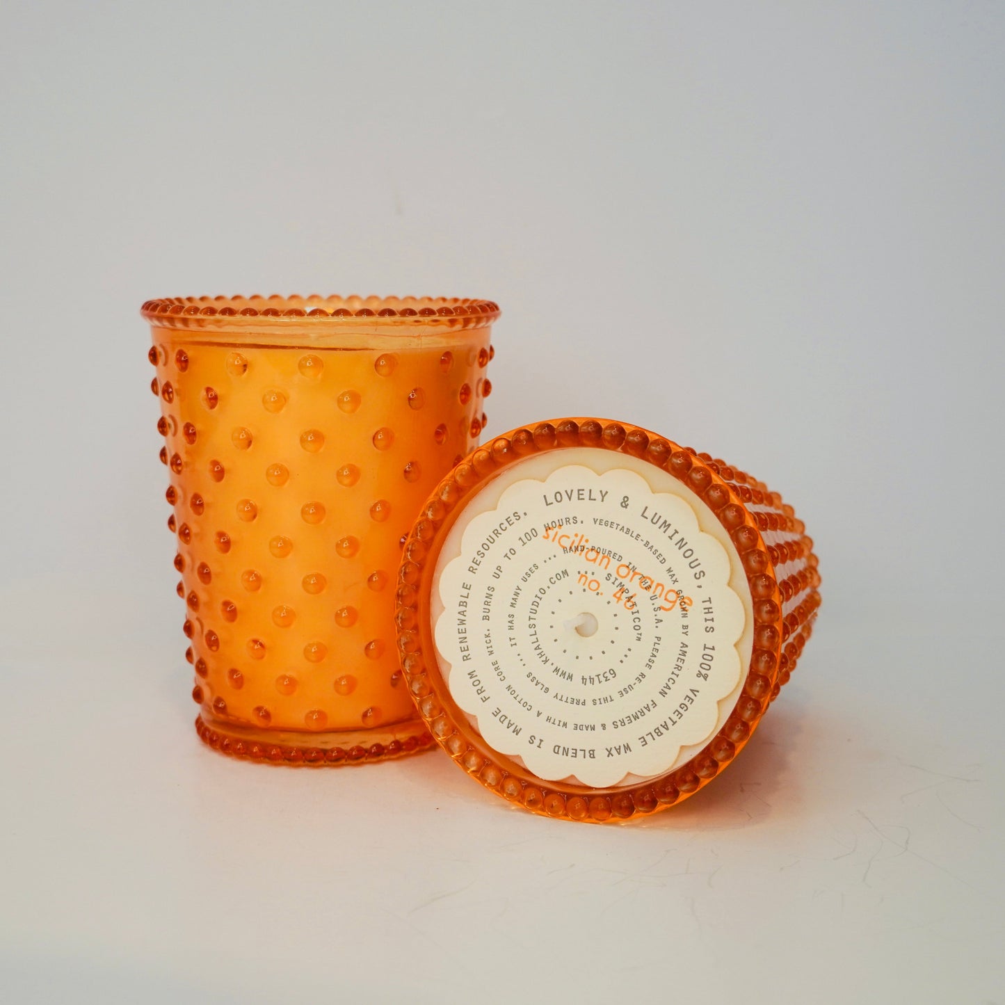 Orange glass container with textured surface and label on a white background
