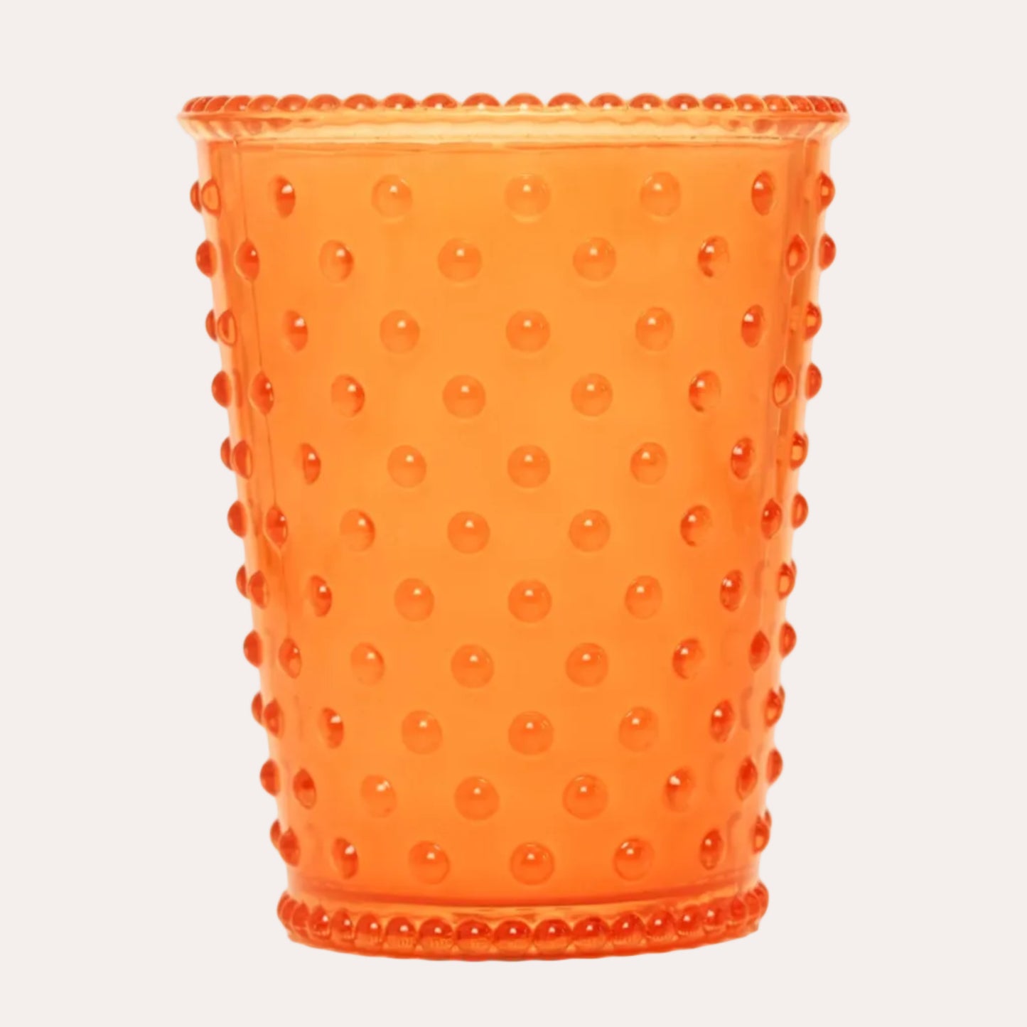An orange hobnail glass tumbler with a beaded rim, featuring a raised dotted texture, isolated on a white background.