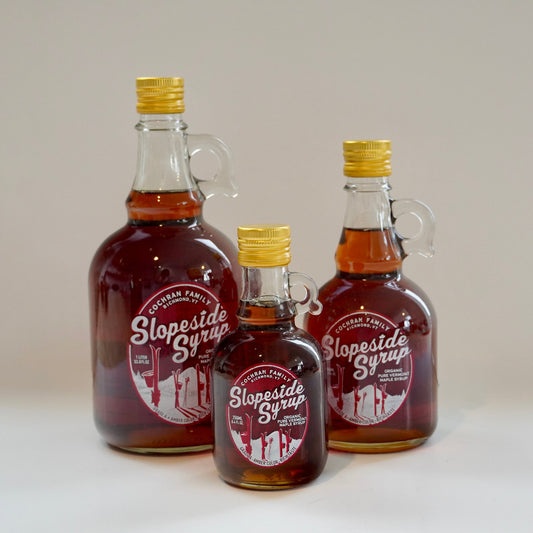Three different sized jars of Slopeside maple syrup on a white background