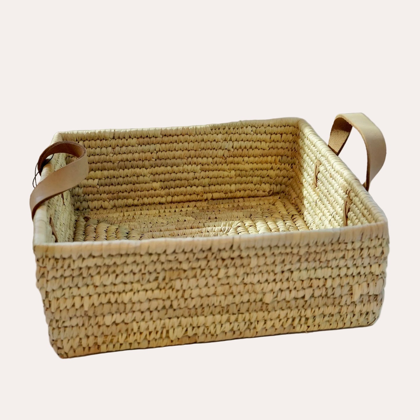 Woven basket with leather handles on a white background