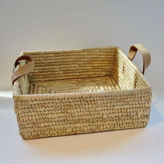 Woven basket with leather handles on a white background