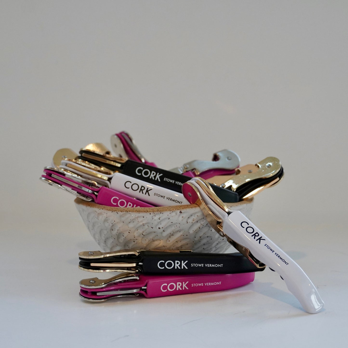 Set of wine bottle openers with 'CORK' branding in a shell-shaped container on a white background